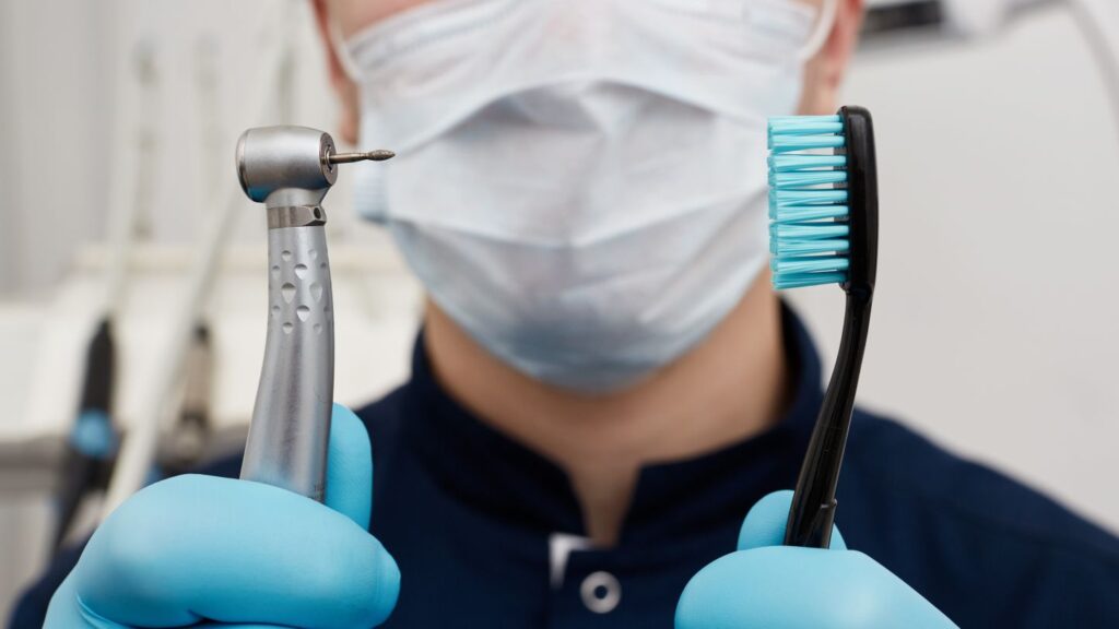 Dental clinician comparing clinical tools and daily oral care with a toothbrush and handpiece