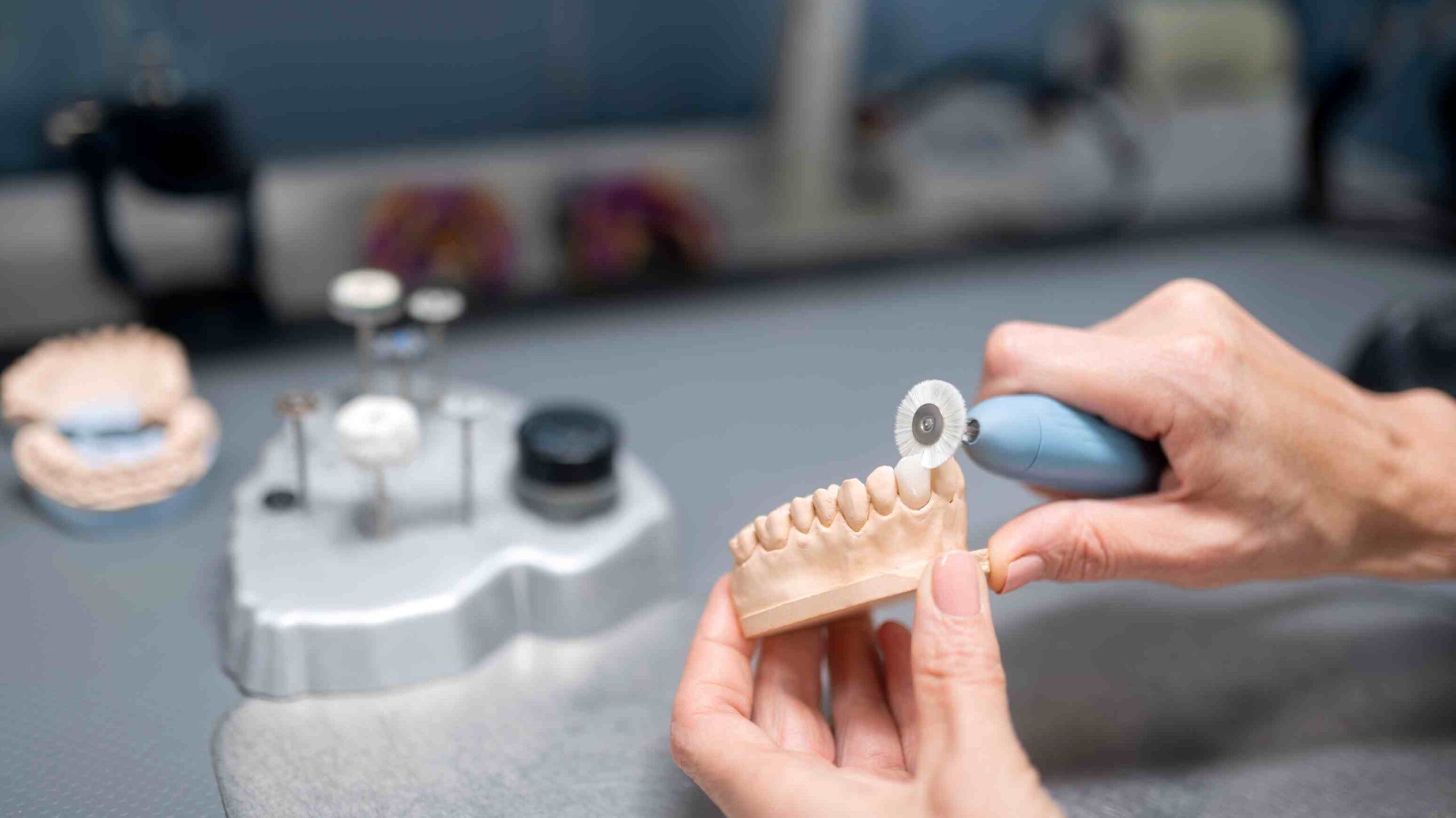 Dental lab technician polishing a ceramic veneer model with precision tools, highlighting how dentist experience and lab quality affect veneer fit and natural-looking results.