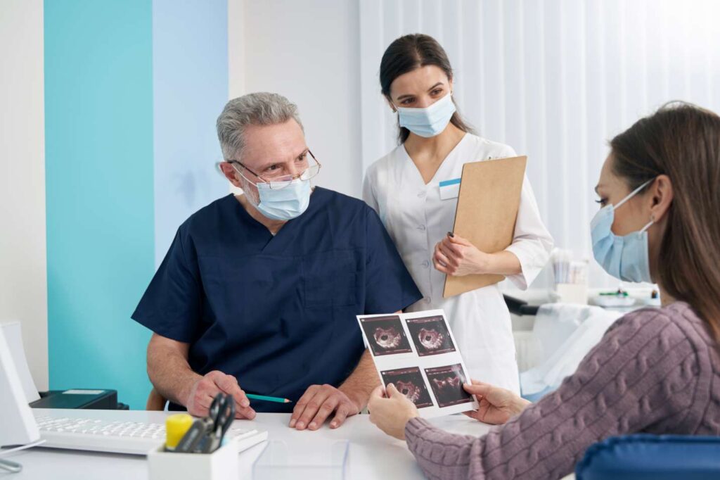 Dentist and dental assistant consulting with a patient and reviewing dental images in a clinic