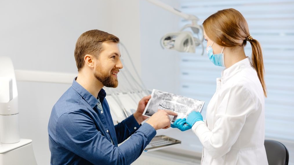 Dentist reviewing a dental X-ray with a patient during a consultation before cosmetic treatment.