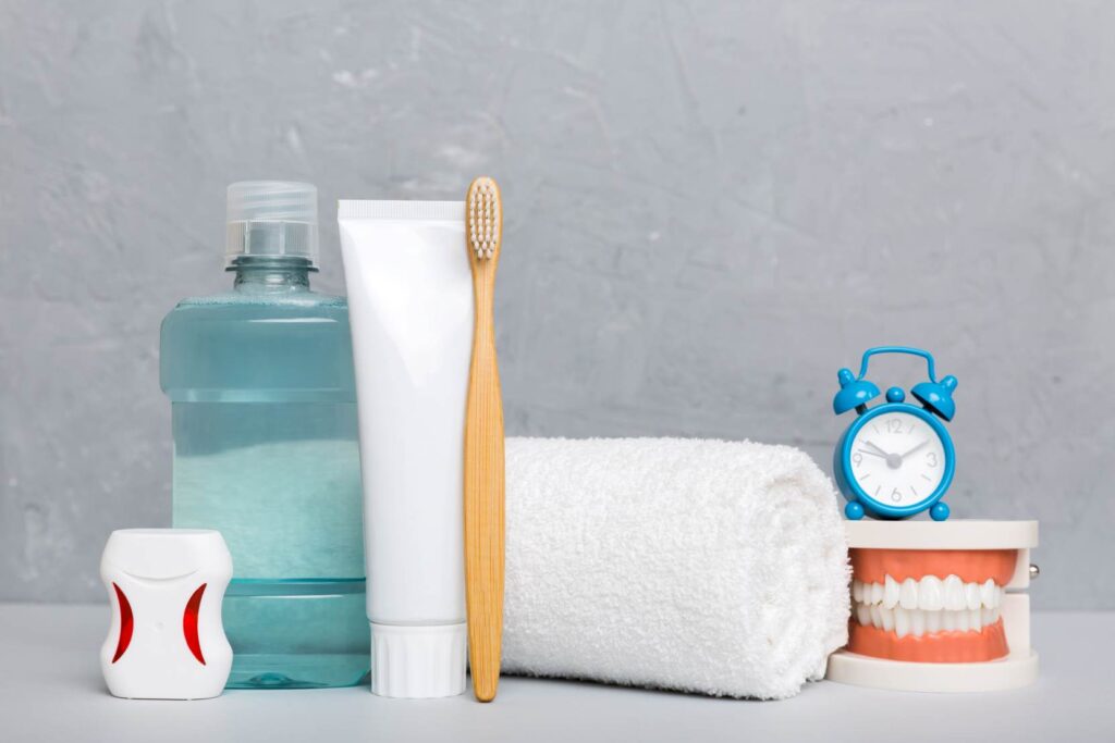 Recovery and aftercare for Hollywood smile steps and timeline, showing toothbrush, toothpaste, mouthwash, floss, towel, and dental model with a clock