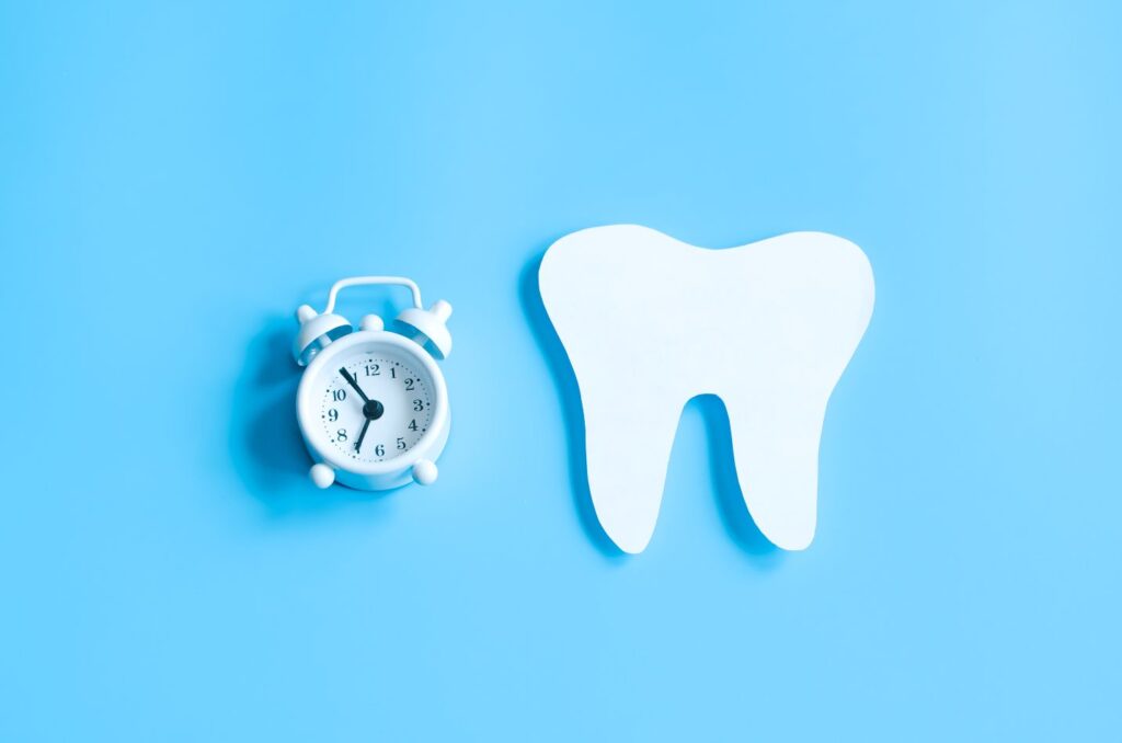 Hollywood smile steps and timeline at a glance with a tooth icon and alarm clock on a blue background