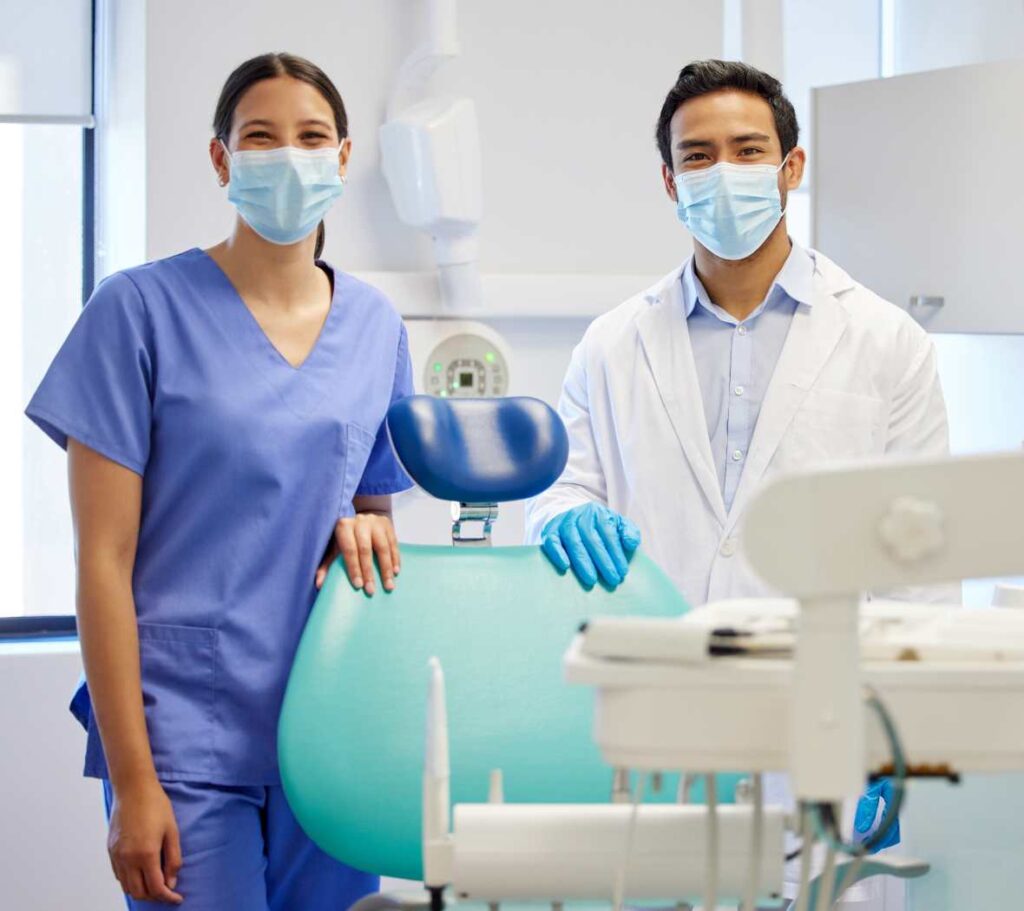 Two dentists wearing masks in a Mexican dental clinic, ready to plan a Hollywood smile treatment