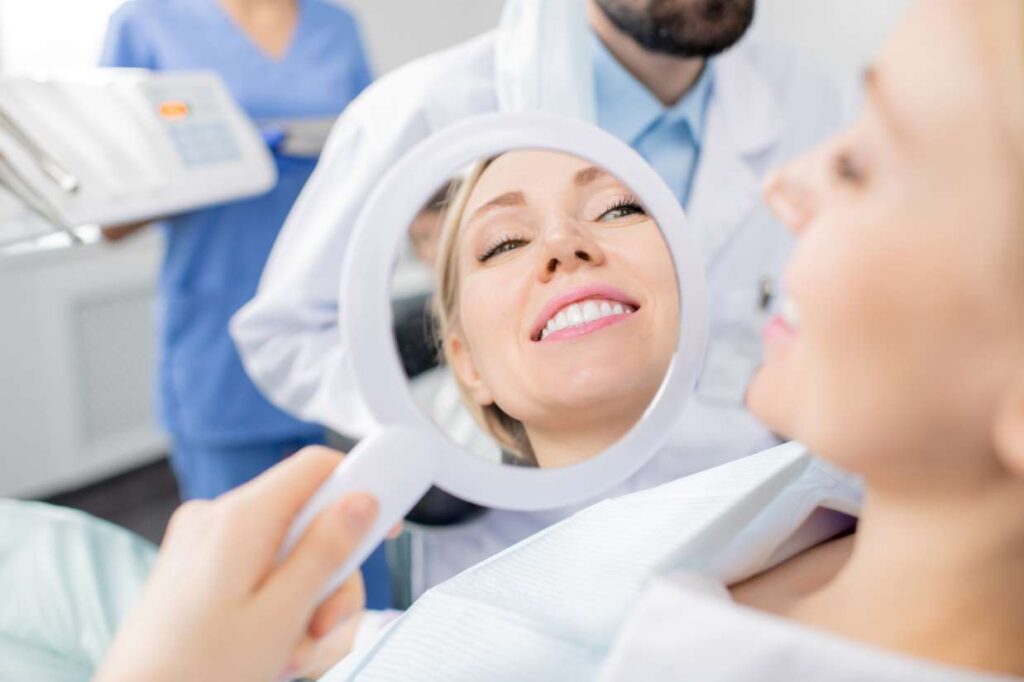Woman checking her new Hollywood smile in a dental clinic mirror after veneer treatment in Spain
