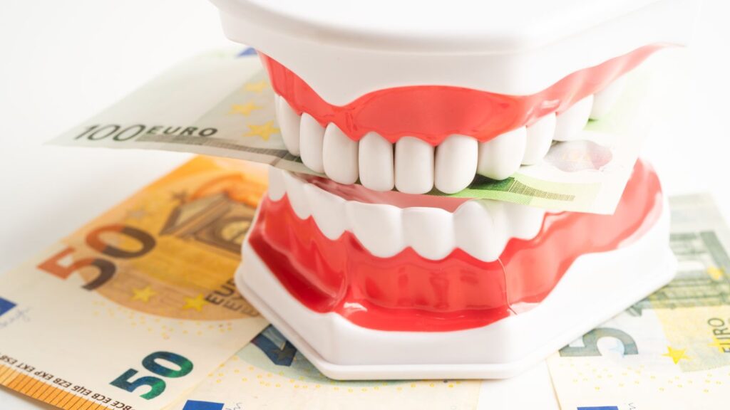 Dental model with veneers on euro banknotes illustrating Hollywood smile cost factors in Poland.