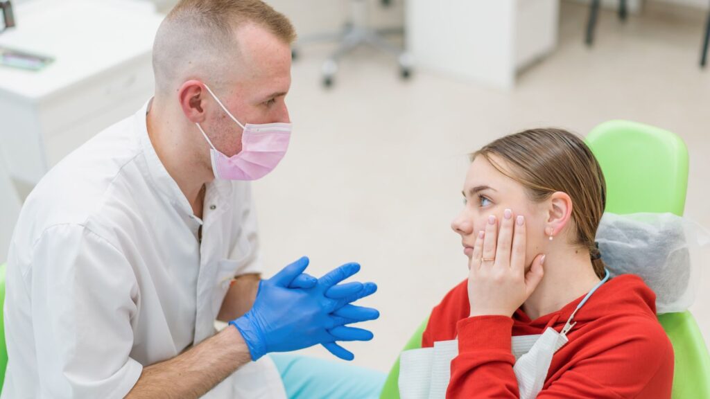 Dentist consulting a patient in a dental clinic, discussing when to see the dentist before cosmetic treatment.