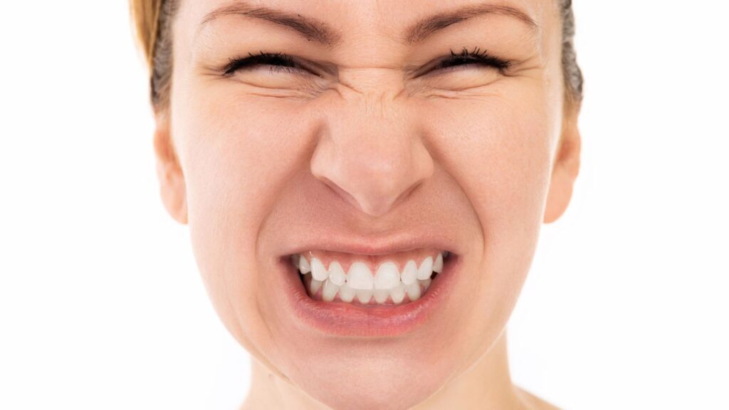 Woman clenching teeth showing bruxism, a common cause of veneers chipping or cracking