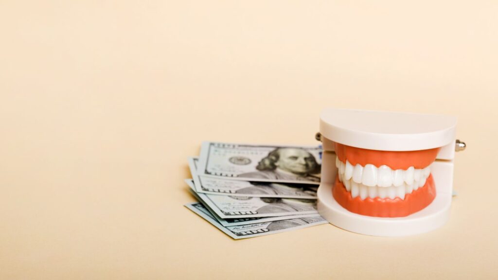 What really drives the cost up or down? Teeth model next to cash representing Hollywood smile pricing factors.