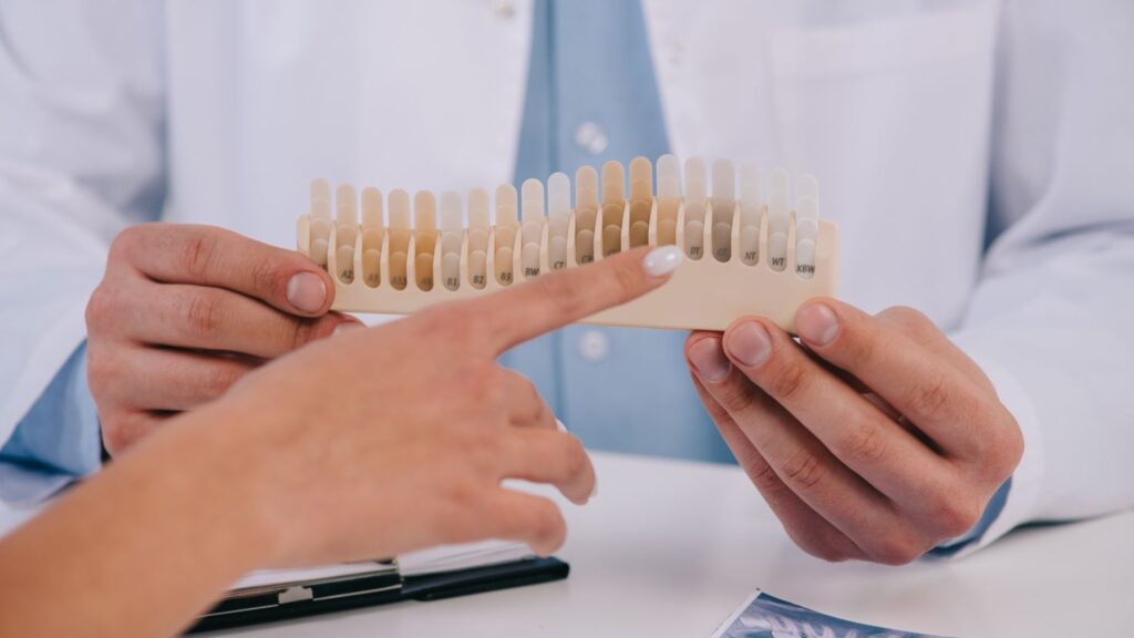 How to choose safely: dentist and patient using a tooth shade guide for Hollywood smile cost in Tunisia.adsddasssdhllkjhgfds;'slslslslsl