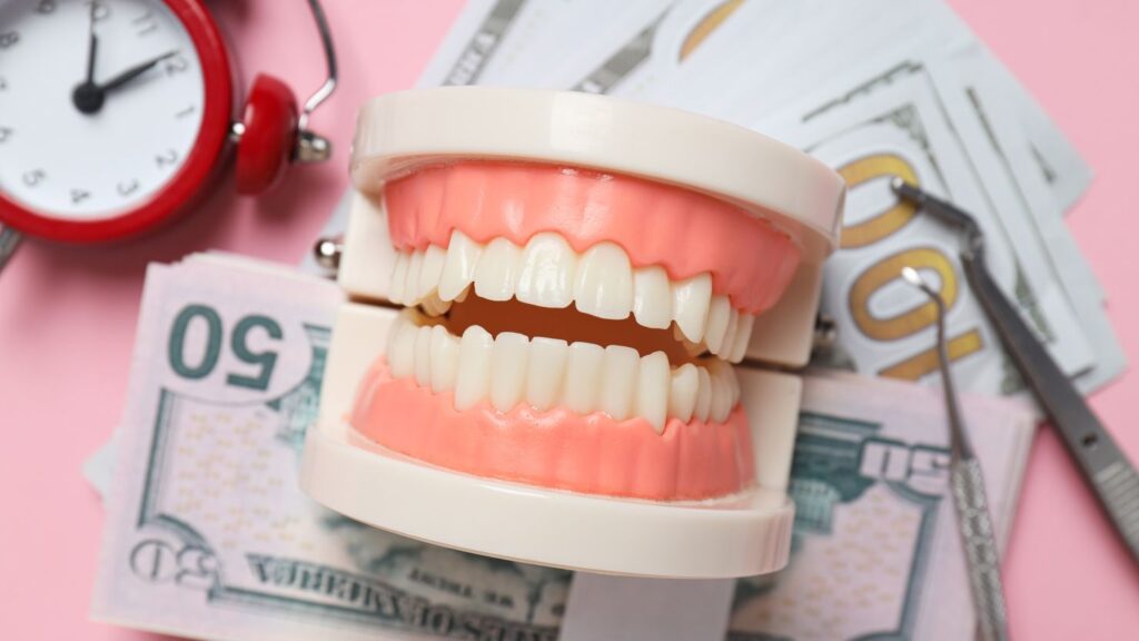 Dental model on banknotes with a clock and dental tools, illustrating why Hollywood smile prices vary in Morocco.