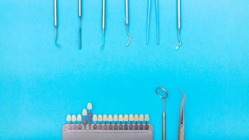 The core risks to understand before you start a Hollywood smile include planning, shown here with dental tools and a tooth shade guide on a blue background.