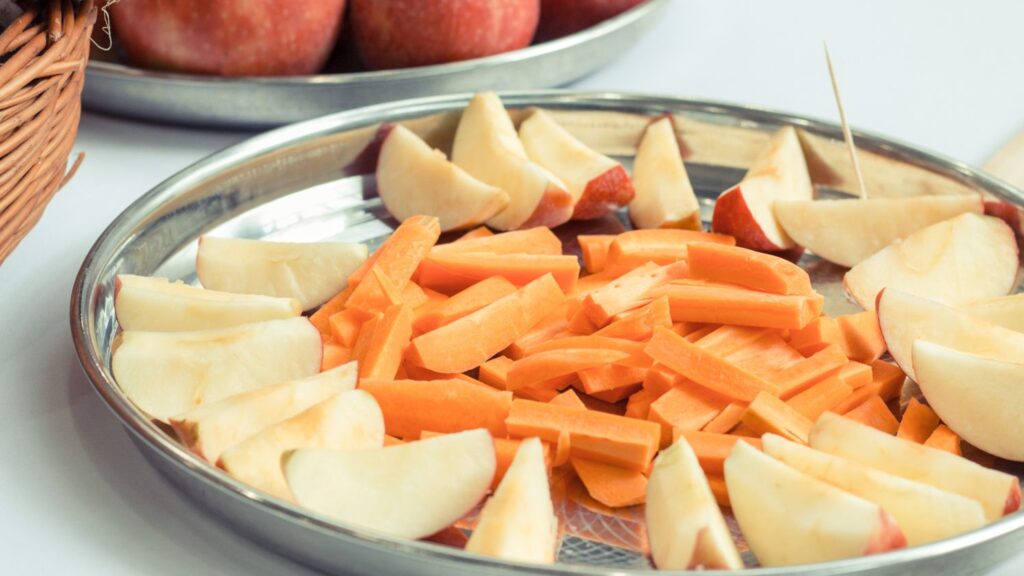 Sliced apples and carrot sticks showing hard foods to avoid biting with front veneers