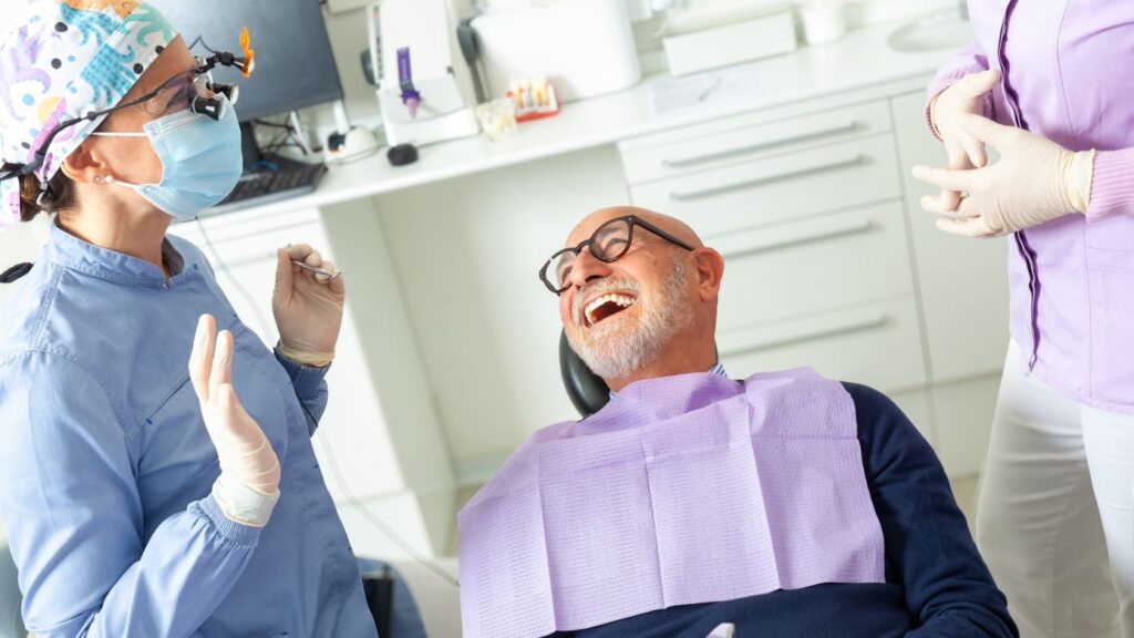 Dentist consults with a smiling patient about veneers vs crowns during a dental exam.