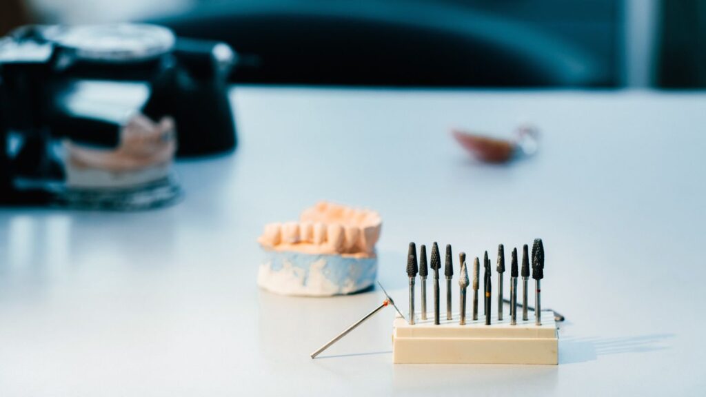 Dental tools and a tooth model on a clinic desk, representing cosmetic dentistry options like whitening, bonding, and veneers.