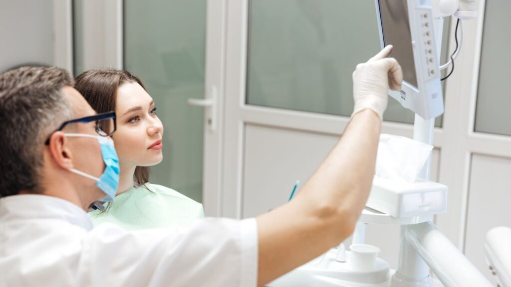 When should I see the dentist about Hollywood smile risks? A dentist consults with a patient and reviews treatment options in a clinic.