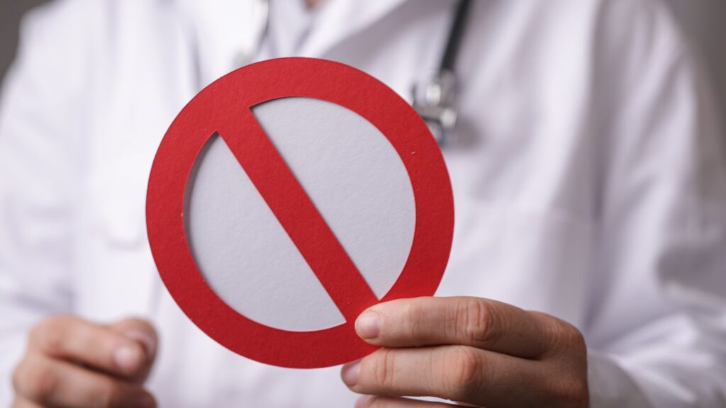 What not to do when a veneer fell off, doctor holding a no symbol