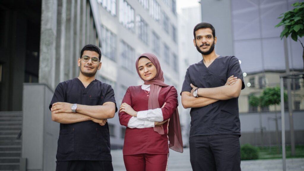 Dental tourism and “package” risks: how to protect yourself when choosing a Hollywood smile clinic, shown by a team of dental professionals in scrubs outside a modern building.