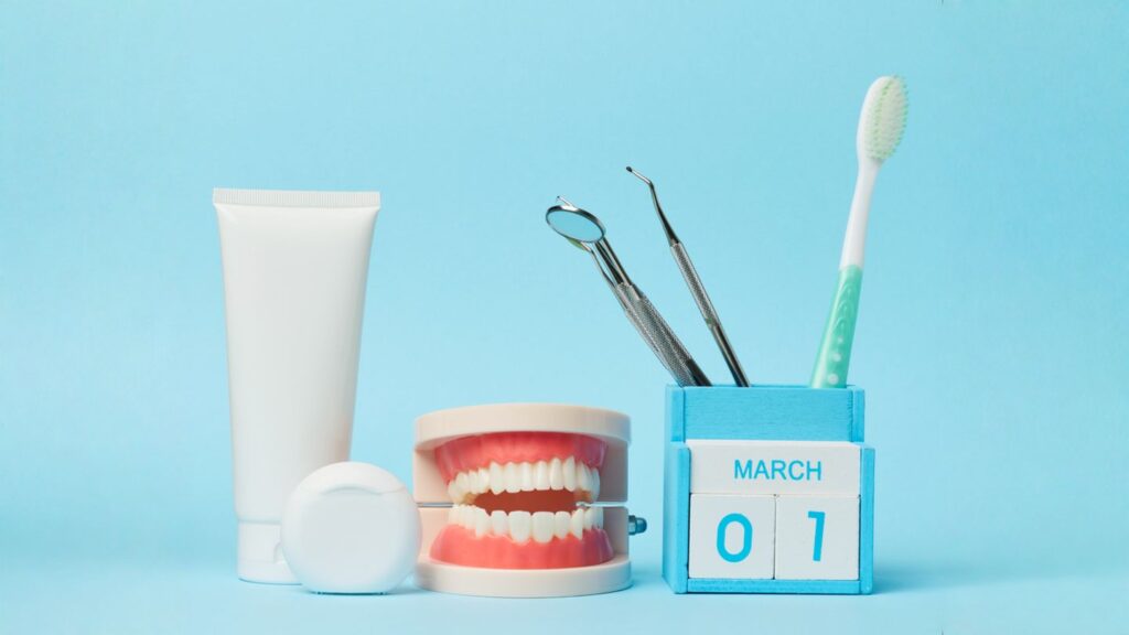 Tooth care tools and a denture model beside a desk calendar showing March 1, illustrating a dental maintenance plan.